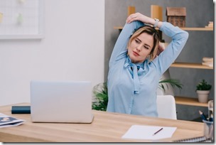 Businesswoman Stretching Shoulders At Workplace In Office