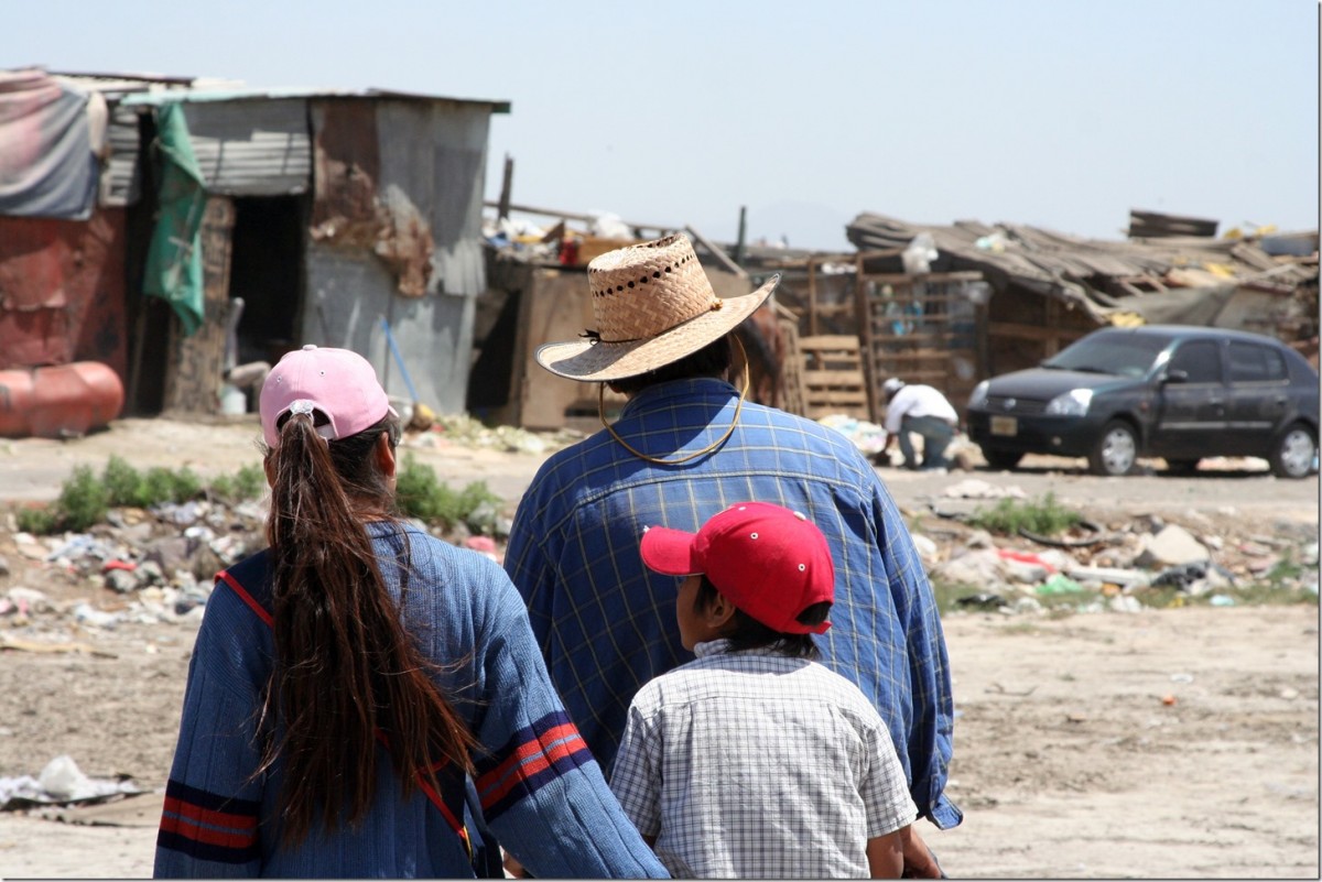 A family is walking to their home at a garbage dump.
