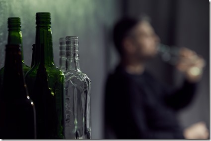 Empty bottles of alcohol with drinking man