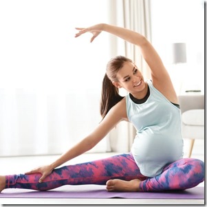 Young pregnant woman in fitness clothes practicing yoga at home. Space for text