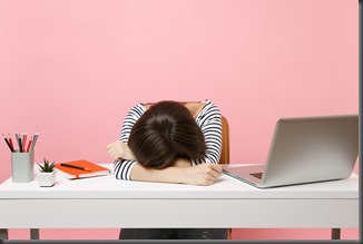 Young Disappointed Tired woman laid her head down on the table sit, work at white desk with contemporary pc laptop isolated on pastel pink background. Achievement business career concept. Copy space.