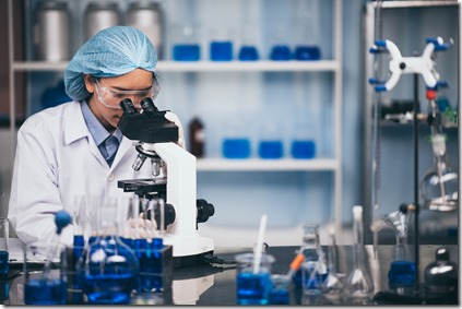 Young scientist looking through a microscope in a laboratory. Young scientist doing some research.