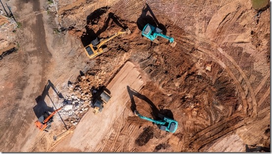 Aerial view road motor grader flatting dirt road surface, Motor grader road construction grader industrial machine construction site new road, Aerial view group excavator working on construction site.
