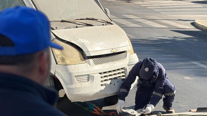 Personal municipal realizando el retiro de un vehículo abandonado en una calle de Antofagasta.