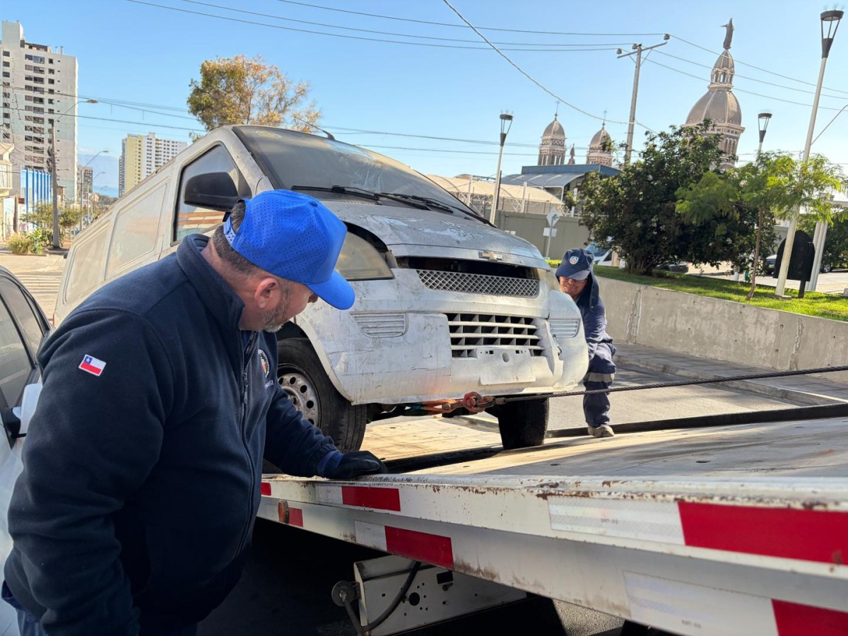 OPERATIVOS MUNICIPALES RETIRAN VEHÍCULOS ABANDONADOS EN ANTOFAGASTA Personal municipal realizando el retiro de un vehículo abandonado en una calle de Antofagasta.