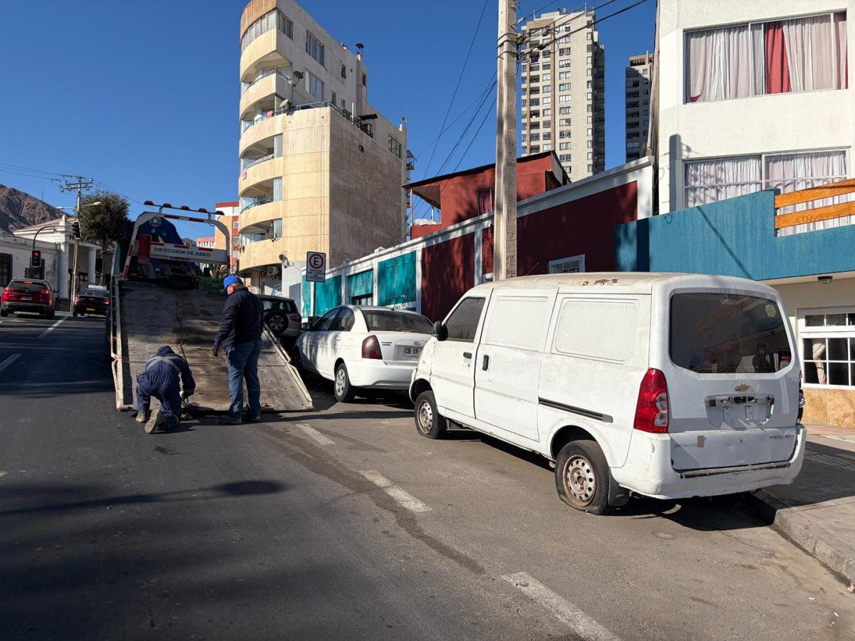 OPERATIVOS MUNICIPALES RETIRAN VEHÍCULOS ABANDONADOS EN ANTOFAGASTA Personal municipal realizando el retiro de un vehículo abandonado en una calle de Antofagasta.