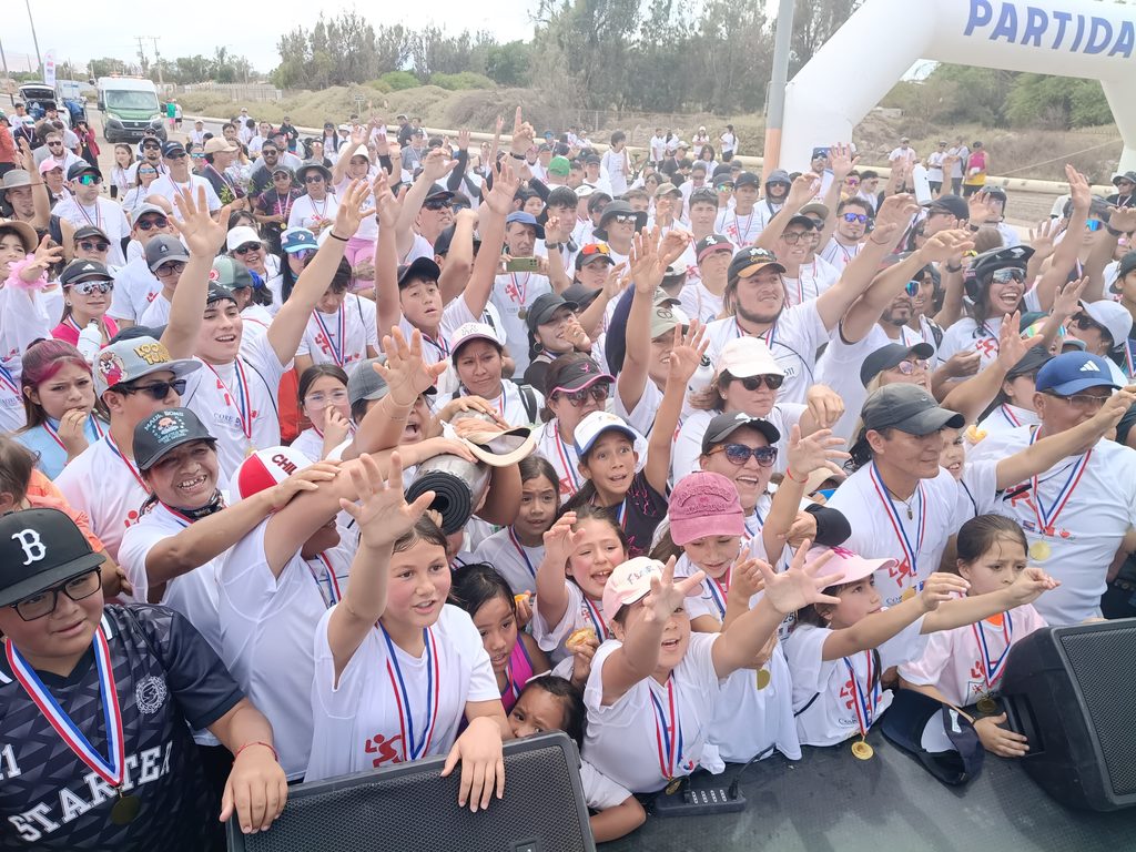 Participantes de la corrida Elige Vivir Sano en Calama celebrando con poleras blancas y entusiasmo