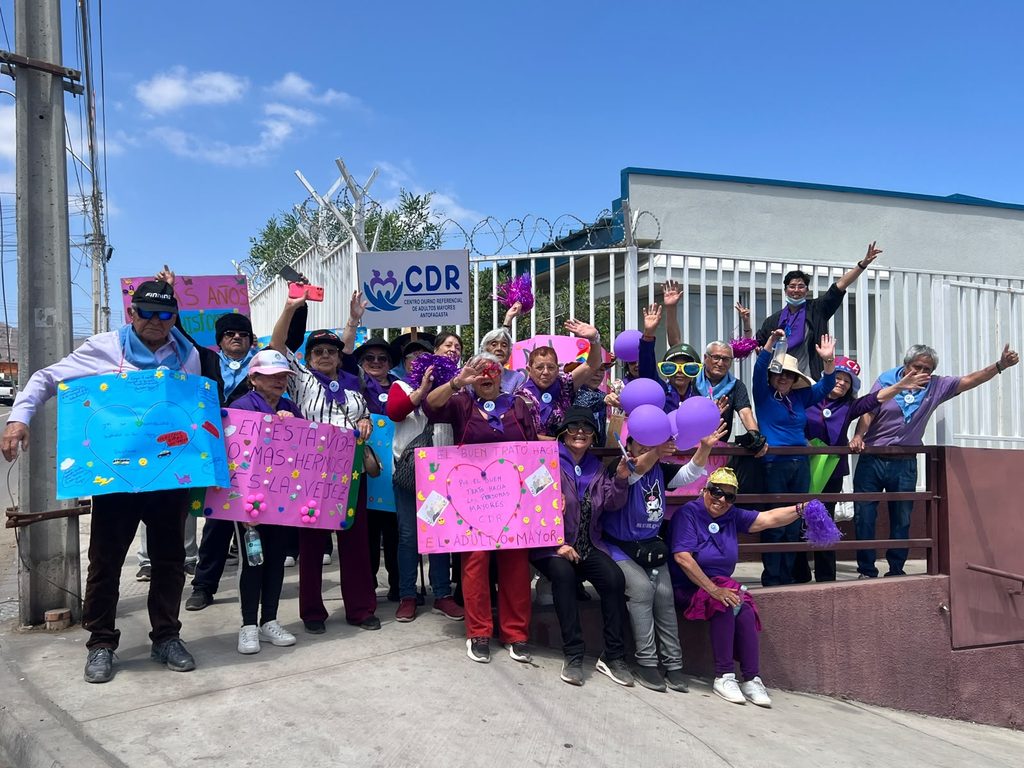 Personas mayores y equipo del Centro Diurno Referencial de la Universidad de Antofagasta participando en una comparsa comunitaria.
